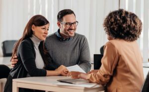 Two adults review shared bank statements and household bills at a kitchen table.
